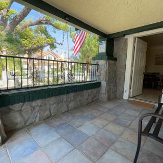 A welcoming porch with tile flooring and a view of an American flag outside.