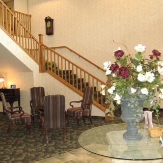 A hotel lobby featuring a staircase, chairs, and a floral centerpiece on a round table.