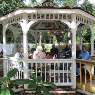 A group of people relaxing in a white gazebo surrounded by greenery.