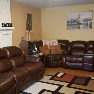 A cozy living room with leather sofas, a patterned rug, and wall art.