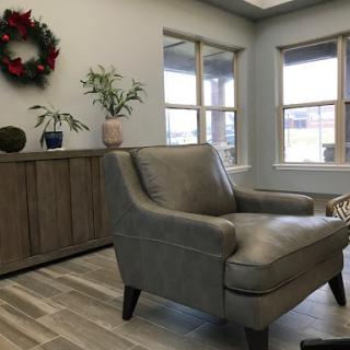 A cozy living room featuring a stylish armchair, decorative plants, and natural light streaming through the windows.