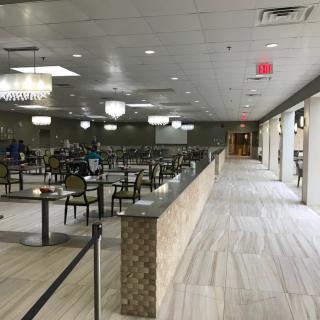 An empty dining hall featuring lined tables and chairs under ceiling lights.