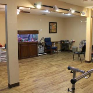 A spacious room with chairs, a fish tank, and exercise equipment, well-lit by ceiling lights.