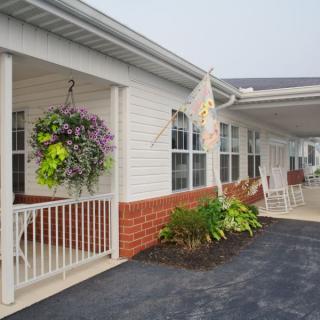 A residential building with a porch, featuring hanging plants and decorative flags.