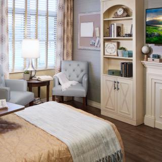 A cozy and traditional bedroom with a comfortable armchair, bookshelf, and warm lighting.