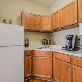 A small kitchen with wooden cabinets, a white refrigerator, and a coffee maker on the counter.