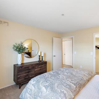 A cozy bedroom with a decorative dresser and a large mirror on the wall.