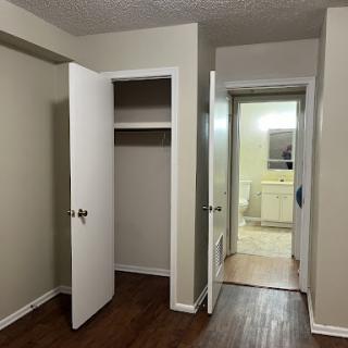 A view of a room featuring an open closet and two doors leading to different areas.