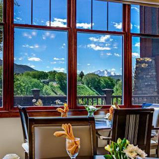 A restaurant interior with a beautifully set table and a stunning view of mountains and nature through large windows.