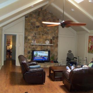 A cozy living room with a vaulted ceiling and stone fireplace features leather seating and a large television.