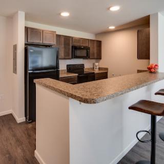 A modern kitchen with an open layout, featuring granite countertops and sleek stainless steel appliances.
