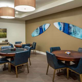 A modern dining area with round tables and blue upholstered chairs, featuring abstract artwork on the wall.
