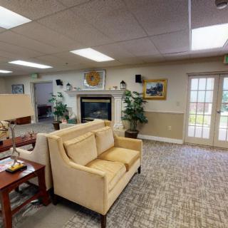 A cozy lobby area with a sofa and fireplace, decorated with plants and artwork.