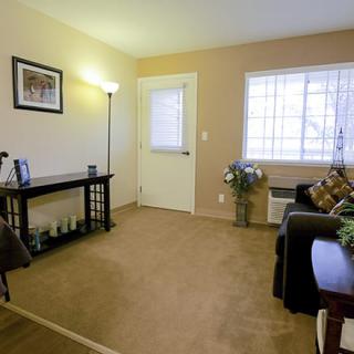A cozy living room with a sofa, table, and lamp, featuring a large window.