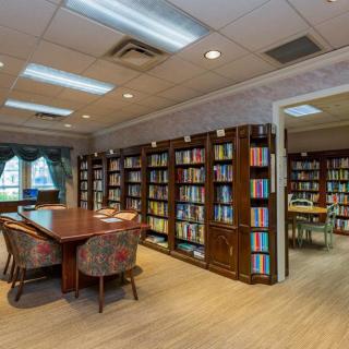 A cozy library with bookshelves and a reading area featuring a table and chairs.