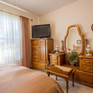A cozy bedroom with wooden furniture, including a dresser with a mirror and a television.