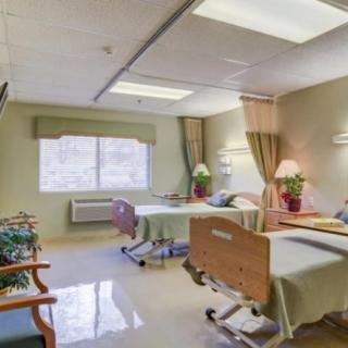 A clean and well-lit hospital room featuring two beds and floral decorations.