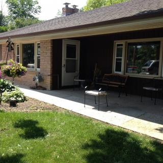 A sunny view of a house with a patio and landscaped yard.
