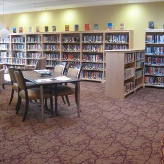 A quiet library with bookshelves, tables, and chairs for reading.