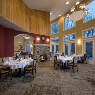 A cozy restaurant dining room with elegantly set tables and a warm fireplace.