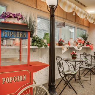 A cozy indoor cafe setting with a vintage popcorn cart and charming bistro seating.