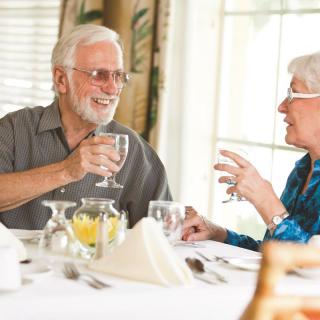 An elderly couple enjoying a conversation over a meal at a restaurant.