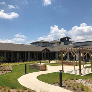 A modern building with a garden and pathway under a clear blue sky.