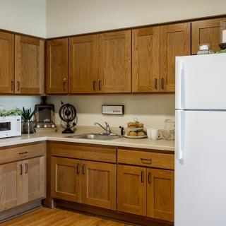 A cozy kitchen with wooden cabinets, a white refrigerator, and various appliances on the countertop.