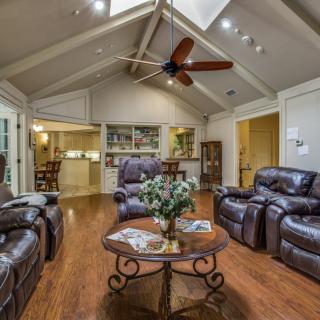 A cozy living room with leather seating, a central coffee table, and a vaulted ceiling featuring a wooden fan.