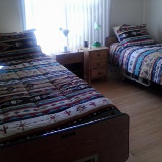 A cozy bedroom with two single beds and a small bedside table.