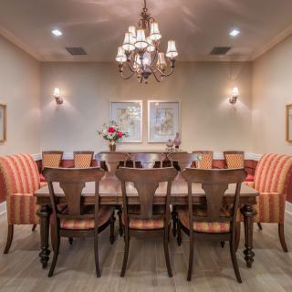 A beautifully decorated dining room featuring a long table and matching chairs under an elegant chandelier.
