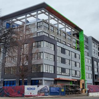 A modern building under construction with scaffolding and cranes.