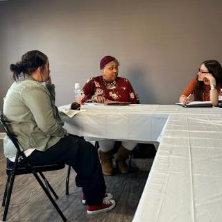 A group of people engaged in a discussion around a table.