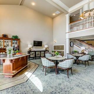 A spacious living room with elegant decor, featuring a staircase, multiple seating areas, and high ceilings.