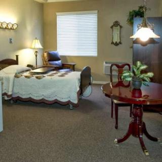 A cozy bedroom featuring a bed, armchair, table, and warm lighting.