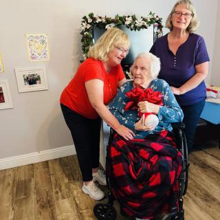 A joyful family gathering with three women, one seated in a wheelchair, celebrating together.