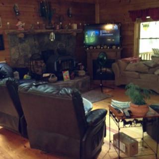 A cozy living room with a rustic cabin vibe, featuring a fireplace and a television.