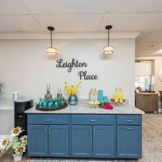 A modern kitchen setup featuring blue cabinets, pendant lighting, and a beverage station.