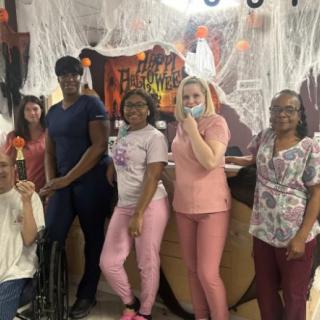 A group of people dressed up in front of Halloween decorations.