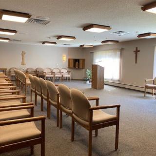 An empty chapel with rows of chairs and a podium at the front.