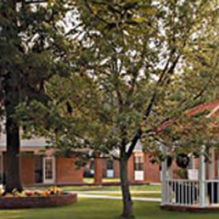 A scenic park area with trees, a gazebo, and nearby buildings.