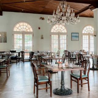 An elegant restaurant interior with a chandelier, featuring neatly arranged tables and chairs.