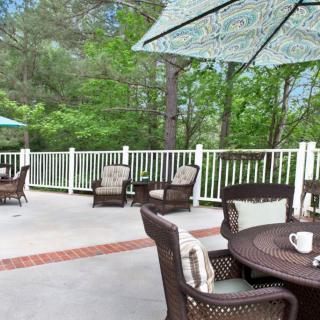 A serene outdoor patio area with comfortable furniture and umbrellas, surrounded by lush greenery.