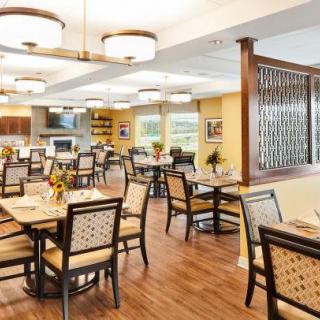 A spacious and elegantly designed dining area with well-arranged tables and chairs, illuminated by stylish lighting fixtures.