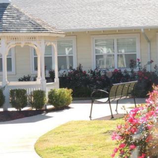 A serene outdoor area featuring a gazebo, bench, and colorful flowers.