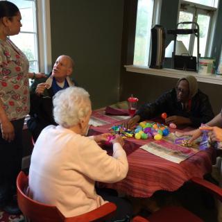 Elderly individuals participating in a group activity with a caregiver in a nursing home.
