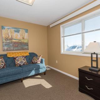 A cozy room featuring a sofa, artwork on the wall, and a window letting in natural light.