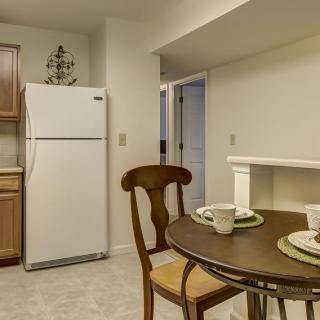 A cozy dining area with a small table, chairs, and a refrigerator in the kitchen.
