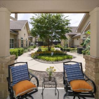 A cozy patio with two chairs overlooks a beautifully landscaped garden and pathway.