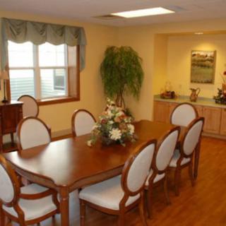 A well-decorated dining room with a wooden table and chairs, featuring a floral centerpiece and nearby greenery.